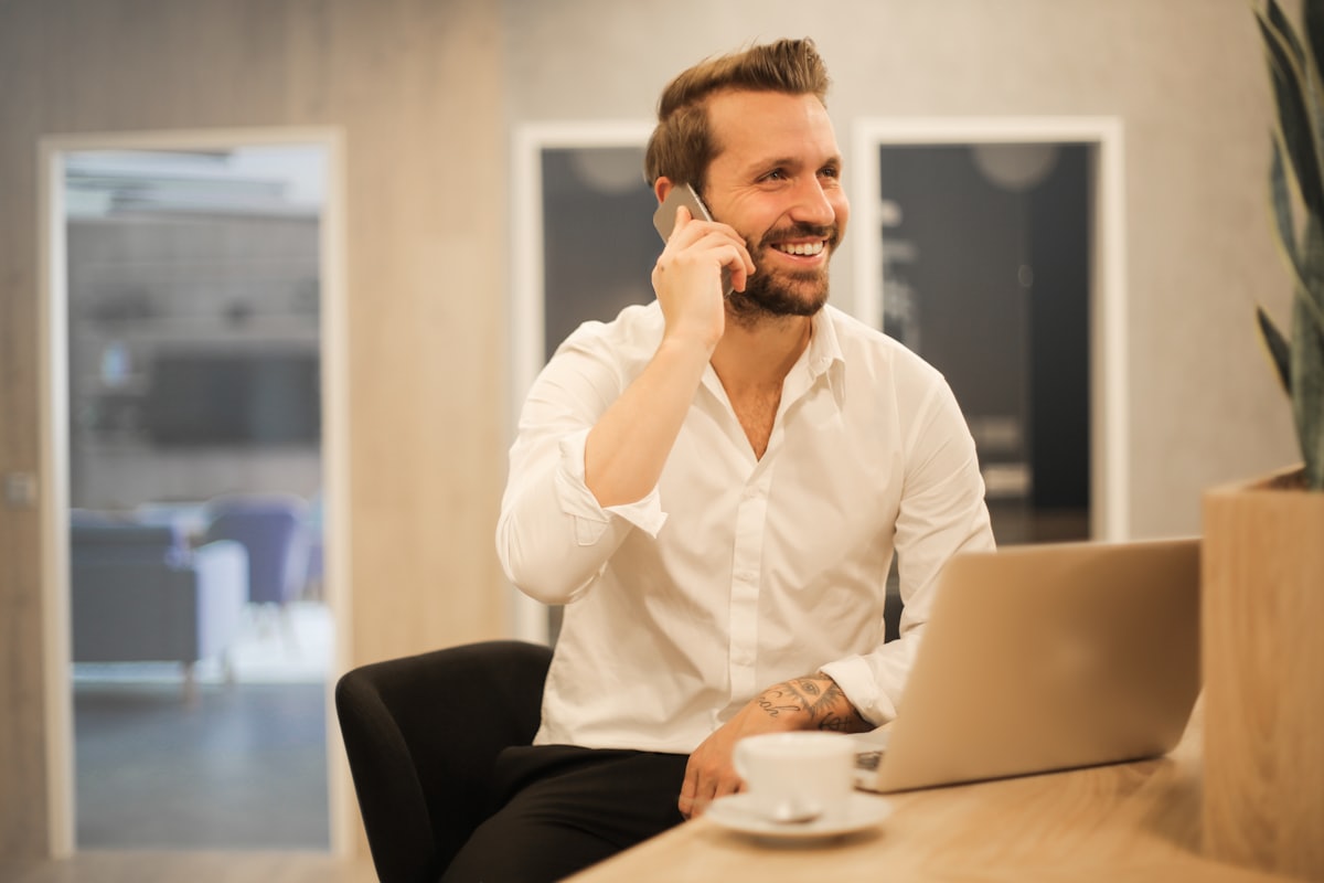 A job seeker smiling during a phone interview with a laptop open
