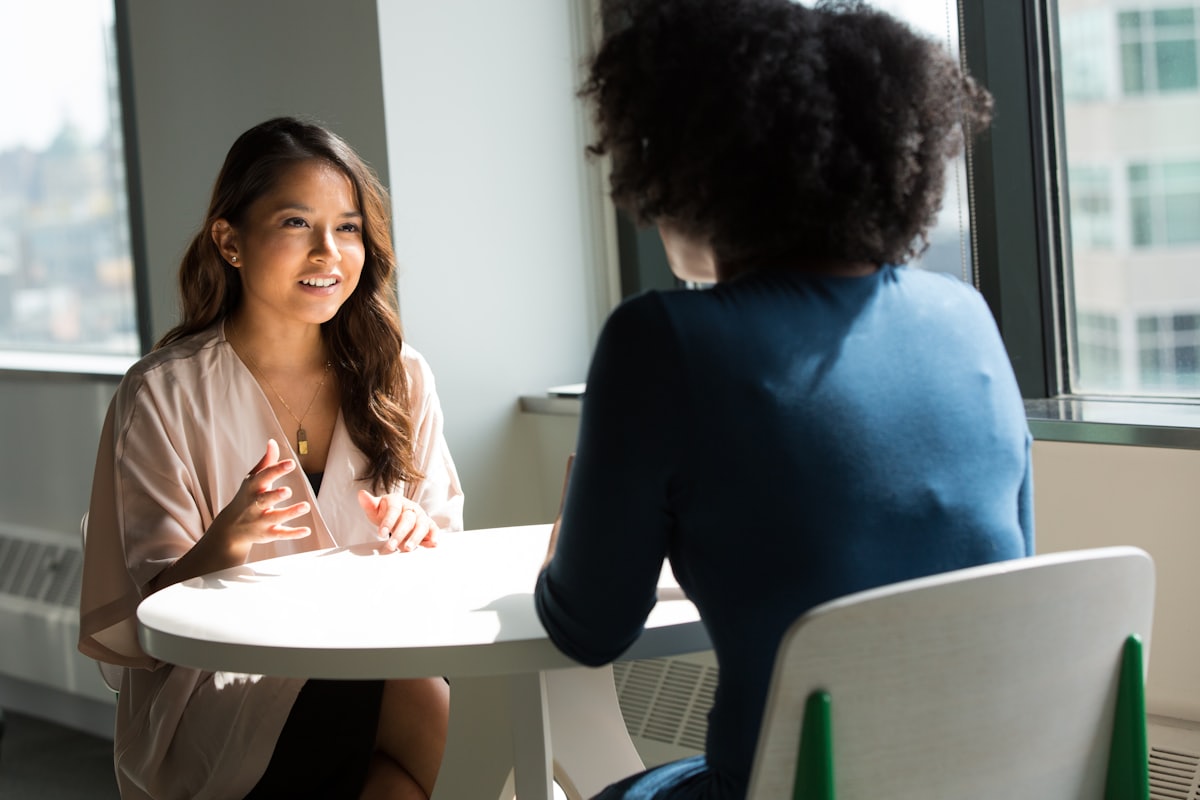 A recruiter interviewing a job candidate across a table in a bright office